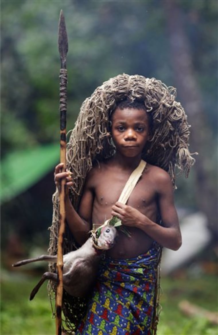 In this March 19, 2010 photo, Oskar Biteye, grandson of family chief Zaire and the group's youngest hunter, returns from the hunt with his day's catch, a forest antelope, in the Okapi Wildlife Reserve outside the town of Epulu, Congo. The pygmies traditional practice of hunting bushmeat has devolved into an all-out commercial endeavor, staged not for subsistence, but to feed growing regional markets. The result: the forests, those that remain, are growing emptier by the day. (AP Photo/Rebecca Blackwell)